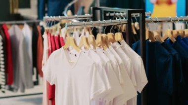Askı ve askılarla dolu boş modern butik, moda mağazasında asılı şık mallar. İndirimli kıyafet ve aksesuarlar müşterilerin gelip satın almasını bekliyor.