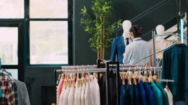 Kafkasyalı işçiler şık ürünlerle neşeli çiftlere yardım ediyor, giysi mağazasında malzeme konusunu tartışıyorlar. Afrika kökenli Amerikalı müşteriler modern butikte şık kıyafetler alıyorlar.