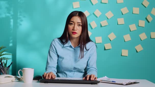 在网络视频会议上 厌倦了过度劳累的亚裔员工一边在电脑键盘上工作 一边听管理层的反馈 在办公室桌上打字和喝咖啡的女商人 — 图库视频影像