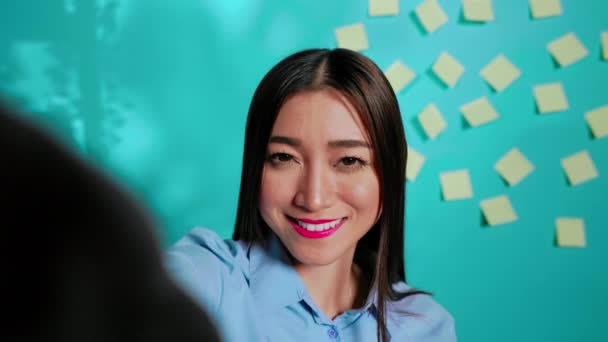 在网上遥测视频通话中 微笑的亚裔员工与有愉快和烦恼情绪的同事聊天 视频会议中的女商人站立时手持网络摄像头 — 图库视频影像