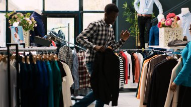 Afrika kökenli Amerikalı çift modern butikte şık mallarla oynaşıp, dans etmekten ve şakacı davranmaktan zevk alıyor. Neşeli insanlar giyim mağazasından şık kıyafetler alıyorlar.