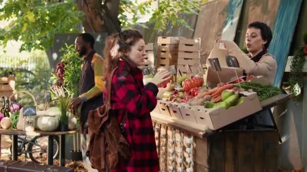 小企业主在摊位上出售新鲜有机产品 与顾客谈论健康饮食和当地的天然蔬菜 向市场摊贩询问生物制品的女性 — 图库视频影像