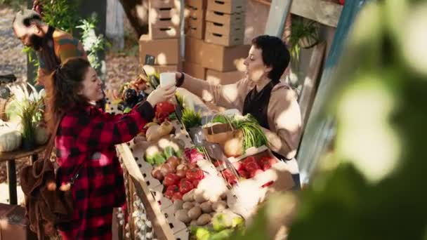 女客户和卖主在农贸市场上喝热咖啡 妇女购买新鲜的生态水果和蔬菜 小企业主销售农产品并享受常客的光临 — 图库视频影像
