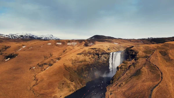凍った崖から落下する北欧のスカガフォスの滝のドローンショットは 美しいアイスランドの風景を作り出します カラフルな丘の上を流れる大規模なスカンジナビアのカスケード スローモーション — ストック写真