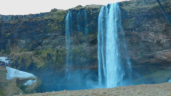 2023年3月左右 在雷克雅未克的塞尔贾兰多斯瀑布 Seljalandsfoss Waterfall 有着冰冷的风景和风景 水流从冰原的悬崖上落下来 丑闻般的瀑布从山丘上流下来 手持射击 — 图库照片