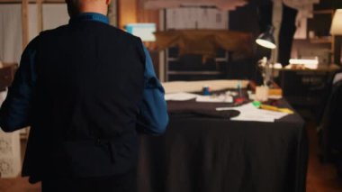 Erkek terzi dikiş işi için kumaş kullanıyor, atölyede lüks kıyafetler tasarlamak için malzeme hazırlıyor. Atölyede deneyimli modacı ürünleri, küçük işletme konsepti..