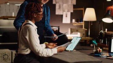 Terzi ve öğrenci atölyede eskizlere bakıyor, giyim markası yaratmak için çıraklık öğreniyor. Deneyimli tasarımcı, terzilik atölyesindeki stajyere yeteneklerini açıklıyor..