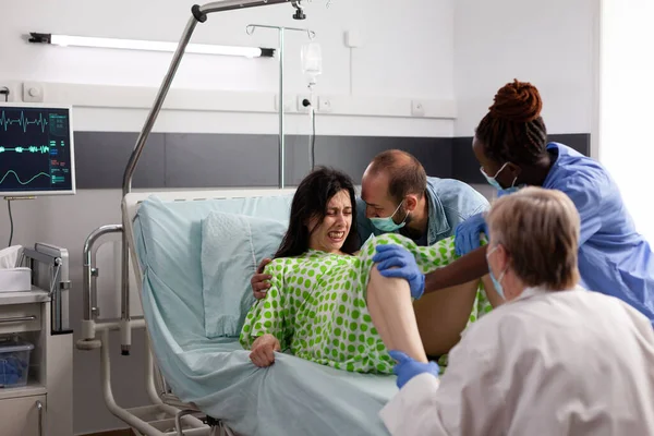 不同的医疗小组在产科医院为分娩时患有阵痛的妇女接生 孕妇分娩时推挤 在医院病房受到丈夫的安慰 — 图库照片
