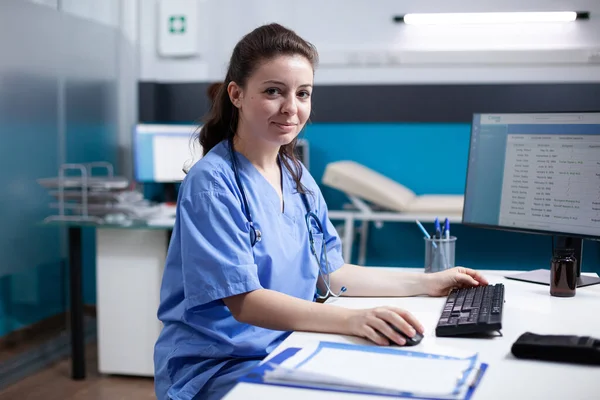 Modern Temiz Klinik Ofiste Masasında Oturan Gülümseyen Beyaz Bir Hemşire — Stok fotoğraf