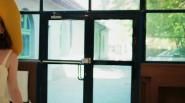 Yaz kıyafetleri içinde kadın gezgin otel lobisine giriyor rezervasyon için resepsiyona geliyor. Bayan misafir resepsiyonistle kayıt ve tatil hakkında konuşuyor. El kamerasıyla..