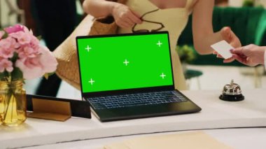 Otelin resepsiyonunda yeşil ekran şablonu olan dizüstü bilgisayar bekleme odasının yanında, resepsiyonda münferit ekran modeli şablonu. Otel lobisindeki PC üzerinde boş kromakey kopyalama alanı.