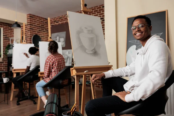 在艺术学校的快乐的非洲裔美国男生的画像 坐在画架前微笑 在课堂上学习铅笔绘图 积极的黑人和朋友们一起享受创造性的业余爱好 — 图库照片