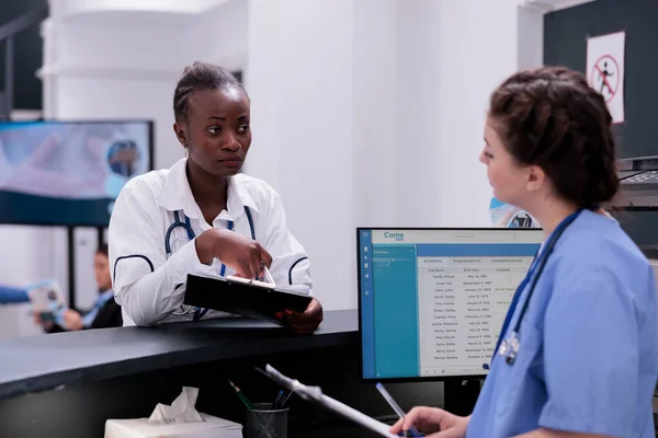 Lekarz Wykazujący Się Wiedzą Medyczną Asystentowi Omawiającemu Objawy Pacjenta Pracującego — Zdjęcie stockowe