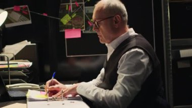 Suç uzmanı adli tıp raporunu analiz ediyor raporlar hazırlıyor, bulmacayı çözmek için belgeler okuyor. Detektif organize suç davasında çalışıyor. El kamerasıyla..