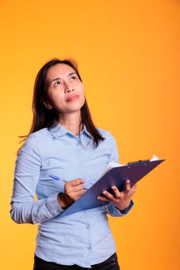 Filipinli kadın ders kitabı dosyaları üzerine notlar alıyor, stüdyoda Busienss için bilgi yazıyor. Düşünceli genç yetişkin evrak işleriyle ilgili yazılardan emin, kontrol listesine bakıyor.