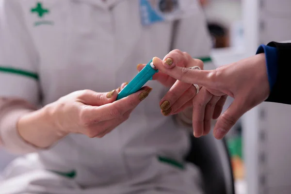 糖尿病のスクリーニングのための血糖値を測定する女性 薬局の従業員は薬局でGlucometerを使用しています — ストック写真