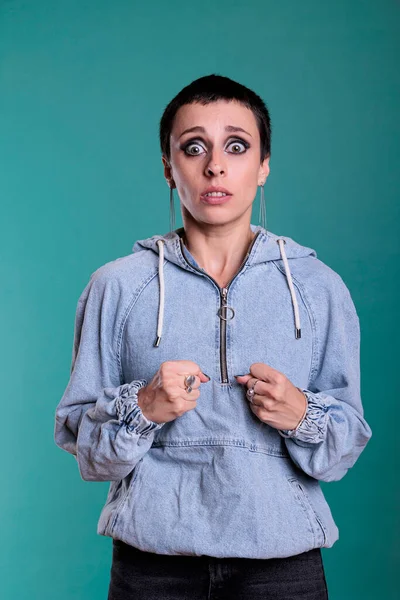 Portrait of afraid brunette woman with short hair having frightened feeling during fashion shot in studio. Afraid caucasian female with terrified facial expression posing over isolated background