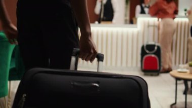 Tramvay taşıyan Afrikalı Amerikalı işadamı, iş gezisi sırasında otel resepsiyonuna geliyor. Resepsiyonist tarafından kontrol edilmeye hazır turist rezervasyon işlemi sırasında, kapatın