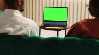 Mutlu Afro-Amerikan turistler dizüstü bilgisayardan video izliyorlar yeşil ekran otelin giriş salonunda otururken taklit ediyorlar. Konuklar kayıt olmayı bekliyor, dinlenme odasında film gösteriliyor.