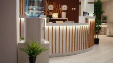 Resepsiyon masasında turistleri karşılamaya hazır boş lüks otel çekimleri var. Rahat bir tatil yeri lobisi. Bitkilerle dolu. Bekliyorlar.