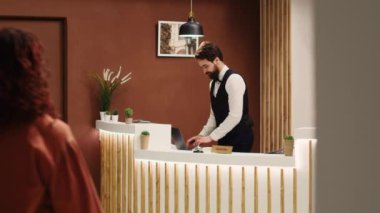 Profesyonel kapıcı, kontrol sırasında resepsiyonda turistleri karşılıyor. Zarif arkadaş canlısı resepsiyon ekibi otel lobisinde tatil misafirlerini karşılıyor.