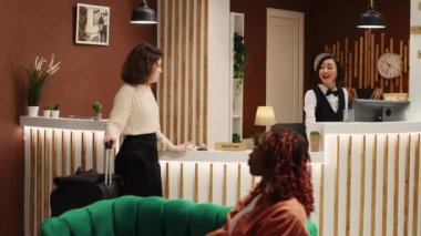 Konuk odasının giriş kartını verirken belboy çalışanı da kontrol sırasında bavullarını taşırken mutlu bir resepsiyonist. Turist ve profesyonel otel personeli dinlenme odasında.