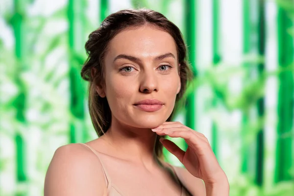 Beautiful smiling woman with fresh skin after using herbal facial cosmetics portrait. Attractive young skincare treatment model holding hand under chin and looking at camera