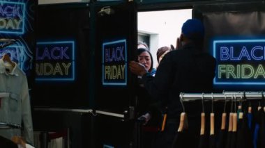 Pazarlık peşinde koşan müşteriler, Kara Cuma 'da mağazaya zorla girmeye çalışıyorlar. Öfkeli müşteriler. Bir grup takıntılı insan alışveriş merkezinin kapılarını ve güvenlik görevlilerini itiyor. El kamerasıyla..