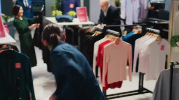 黒い金曜日の割引中にファッションセンターで買い物をしながら ラックから服を選択するお客様 クリアランス ショッピングの衣類アイテムを見て多様な取りつかれた人々 — ストック動画