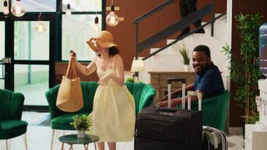 Resepsiyona kayıt yaptırmak için bekleyen gezginler tropik modern tatil beldesindeki egzotik deniz kenarı tatili için mutlu hissediyorlar. Konuklar kayıt yaptırmadan önce dinlenme odasında oturuyorlar..