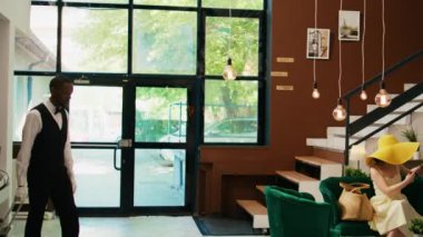 Lobide valiz taşıyan otel komisi, deniz kenarındaki egzotik otellere giriş yapan turistlere mükemmel bir belboy hizmeti sunuyor. Afro-Amerikan işçiler konuklara yardım ediyor..