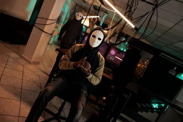 匿名のマスクを持つ犯罪者は 夜に身代金を要求し ライブ放送で政府のデータを公開することを脅かす 若い泥棒は コンピュータシステムをハッキングし セキュリティサーバーに侵入 — ストック写真