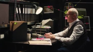 Kıdemli dedektif olay odasındaki gizli kayıtları okudu, suçu çözmeye ve gizli ipuçlarını bulmaya çalıştı. Tanık ifadelerini ve adli kanıt raporlarını inceleyen bir adam..