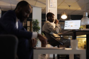 Afrika kökenli Amerikalı yönetici şirket stratejisi planlamadan önce kahve içiyor, pazarlama grafiklerinde gece geç saatlere kadar çalışıyor. İş yönetimi kavramı