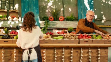 Kıdemli çiftçi organik taze meyve ve sebze satıyor, sebze kutularını ve biyolojik doğal ürünleri düzenliyor. Yerel satıcılardan oluşan bir ekip ev yapımı ürünlerle müşterilere yardım ediyor. Üçayak atışı.