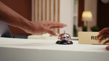 Resepsiyondaki servis zilini çalan Afrikalı Amerikalı turistlerin yakın çekim görüntüleri. Tatil gezisi turistleri otelin resepsiyonuna giriş yapmaya hazır.