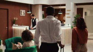 Profesyonel arkadaş canlısı resepsiyon ekibi tatil gezisinde turistleri karşılıyor. Otel resepsiyonundaki konukları karşılama sürecinde yardımcı kapıcı personel.