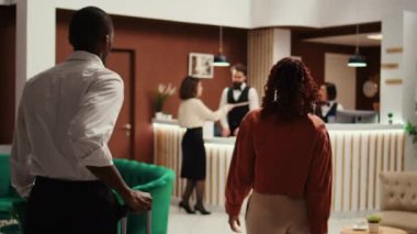 Otel müdürü giriş sırasında resepsiyonistlere rezervasyon dosyalarını veren ziyaretçilere teslim ediyor. İş seyahati konuklarına resepsiyon lobisindeki yardımcı personel çalışanları yardım ediyor.