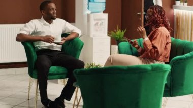 Otel lobisinde mutlu misafirler güzel bir tatilden sonra kominin valiz getirmesini bekliyor. Neşeli Afro-Amerikan çifti otelin dinlenme odasında bir fincan kahvenin tadını çıkarıyor.