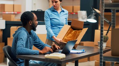 Diverse employees shipping storage products from warehouse, looking at merchandise in boxes before sending package order. Checking inventory and stock, working on distribution logistics.