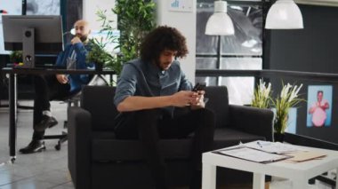 Akıllı telefon uygulaması hakkındaki verileri araştıran yönetici yardımcısı, toplantı odası sunumu için yıllık istatistik raporunu doğrulamak için aygıt kullanıyor. Yetişkin bir çalışan cep telefonuyla iş yerinde çalışıyor..