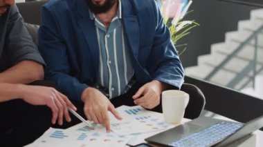 Ofisteki küçük işletmeler için başlangıç ekibi planlaması raporları incelemek için çalışma alanında toplanıyor. Analizleri dizüstü bilgisayardan ve belgelerden kontrol eden genç iş arkadaşları, yürütme stratejisi.