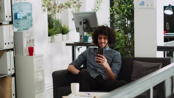 Gerente Executivo Usando Smartphone Sofá Escritório Espaço Aberto Desfrutando Pausa — Vídeo de Stock