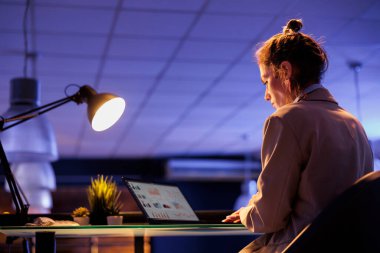 İşletme ofisindeki masa başında oturan yönetici şirket stratejisi planlama planlarını analiz ederek karı artırıyor. İş kadını gece geç saatlere kadar çalışan pazarlama grafikleri