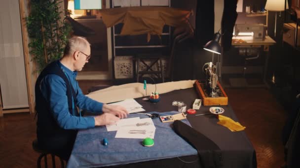 Досвідчений Кутюр Аналізує Ескізи Вибору Сучасної Моделі Одягу Виробництва Предметів — стокове відео