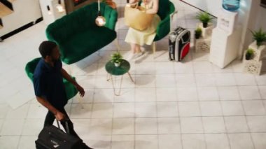 Otel misafiri resepsiyon lobisine giriyor, egzotik deniz kenarı tatiline kayıt olmaya hazırlanıyor. Yaz tatili çalışanları yolculara lüks hizmetler sunuyor. El kamerasıyla..