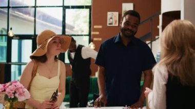 Resepsiyonda kayıt belgelerini dolduran konuklar tropik oteldeki resepsiyonda resepsiyon görevlileriyle kontrol işlemleri yapıyorlar. Balayı gezginleri lüks otellerde kayıt yaptırıyor. El kamerasıyla..