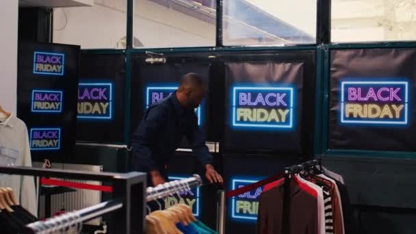 買い物客は 黒い金曜日の大規模な販売の間に服を購入しようとして 店に入る赤いテープを押してください 外で待っている不安クレイジーな顧客の群衆の圧力の下で働く警備員 — ストック動画
