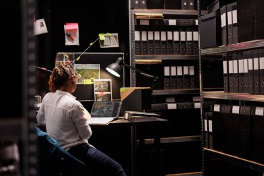 Analiz yapan özel dedektif teşkilat ofisinde gözetim bilgileri topladı. Çalışma masasında oturan kadın dedektif, şüpheli fotoğrafa dizüstü bilgisayarda bakıyor ve ipuçlarını inceliyor.