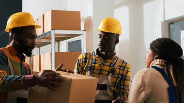 Depo çalışanları depo malzemeleri ve depo ürünleriyle mal paketleri hazırlıyorlar. Raflardan ve raflardan mal alan işçiler, lojistik ve dağıtım üzerinde çalışıyorlar..